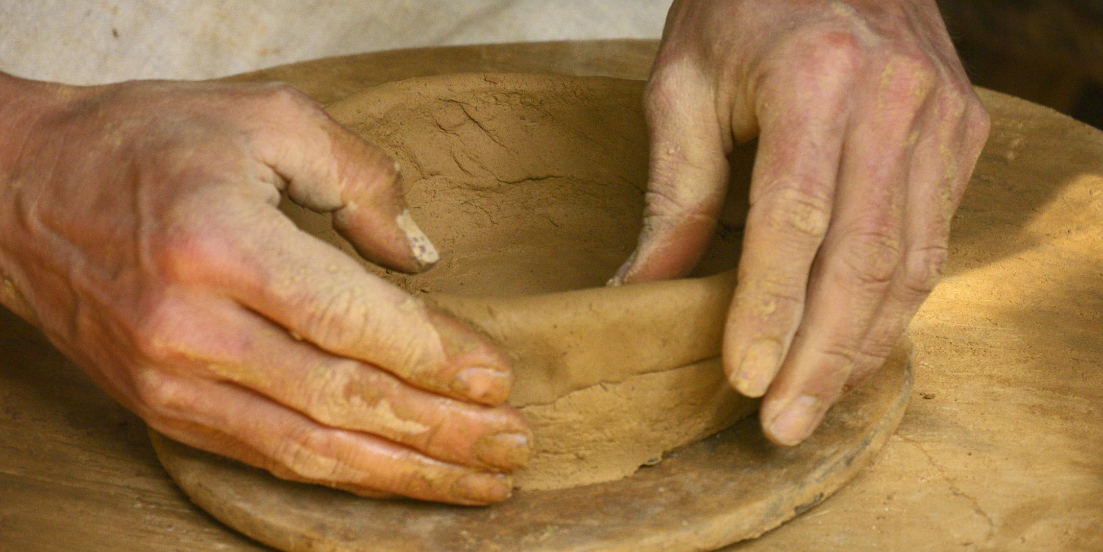 Zwei Hände bauen - Schicht für Schicht - eine Schale aus Ton auf.