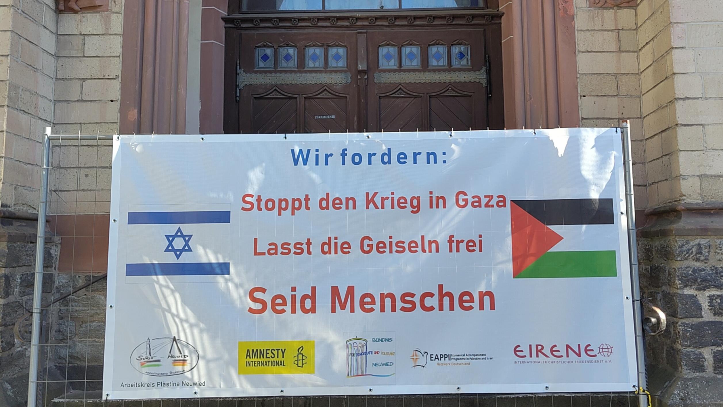 Auf dem Plakat zur Mahnwache steht: 'Wir fordern: Stoppt den Krieg in  Gaza - Lasst die Geiseln frei - Seid Menschen'. Dazu sind die israelische und die palästinensische Flagge, sowie die Logos der Veranstaltenden abgebildet.
