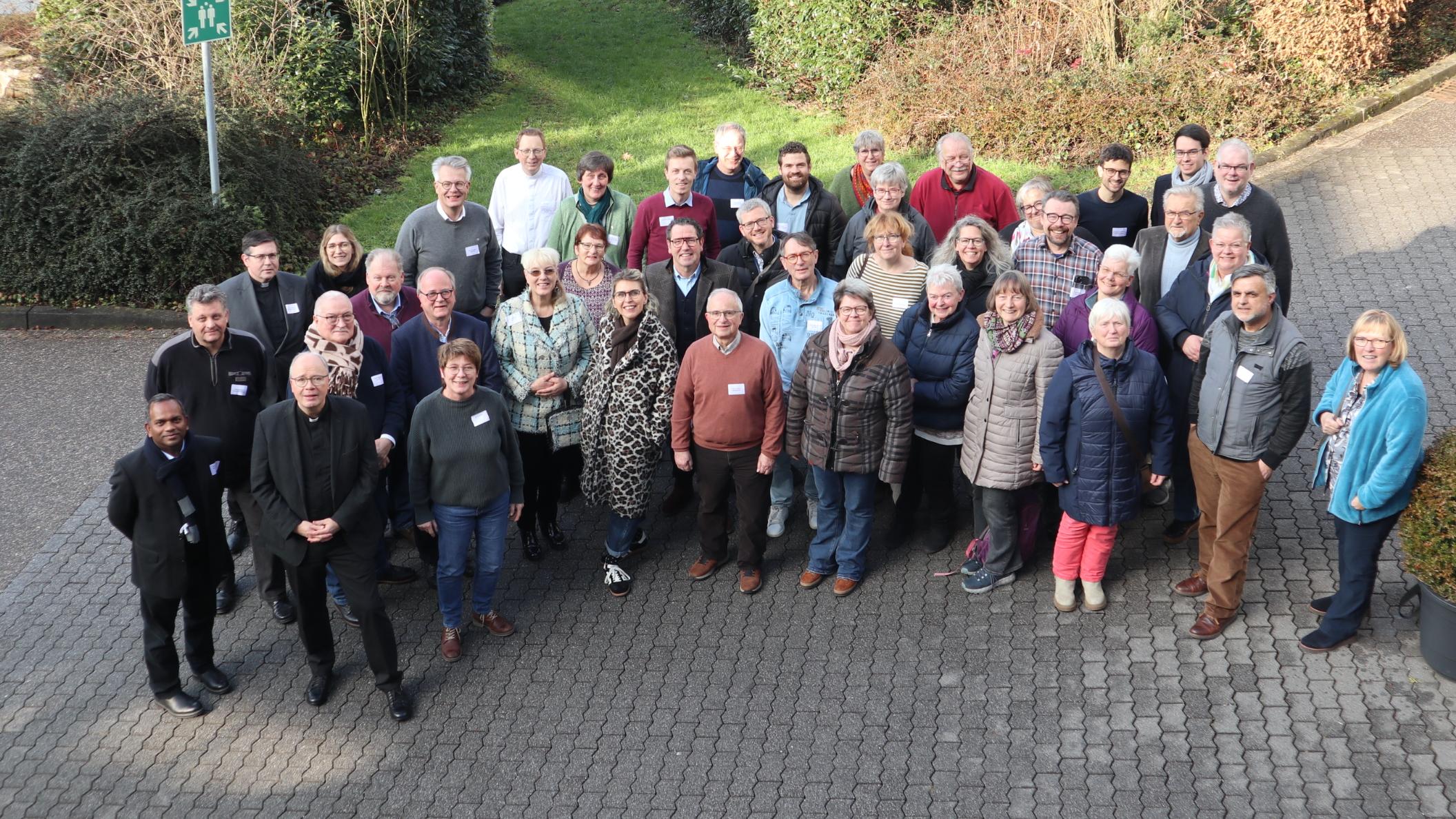 Die Teilnehmenden - zum Teil in Winterjacken - stehen zusammen mit Bischof Ackermann gut gelaunt als Gruppe zusammen und schauen zur Fotografin hinauf.