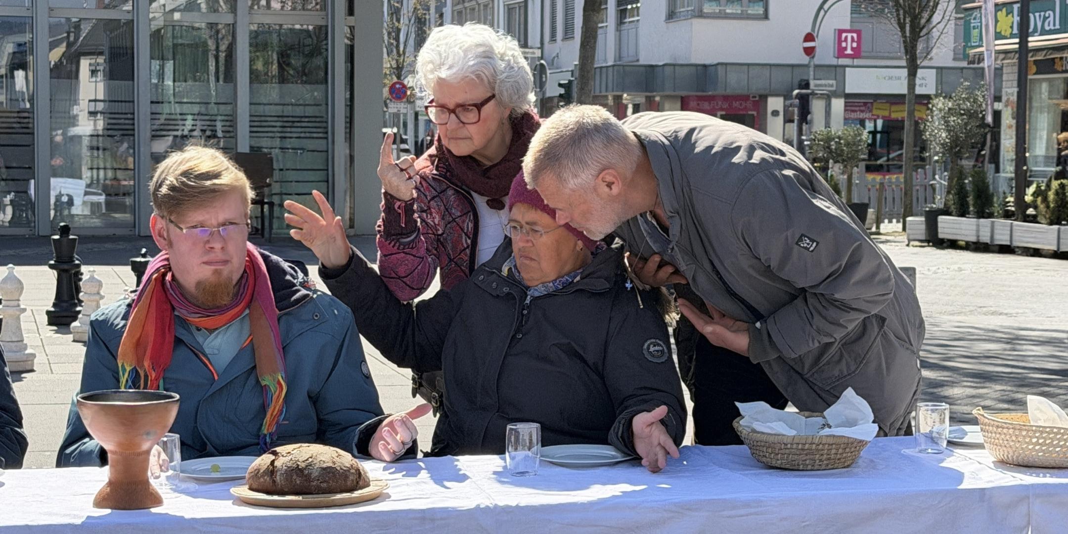 Der Jesus-Darsteller sitzt im Rollstuhl. Drei weitere Darsteller im fortgeschrittenen Alter beugen sich zu ihm.