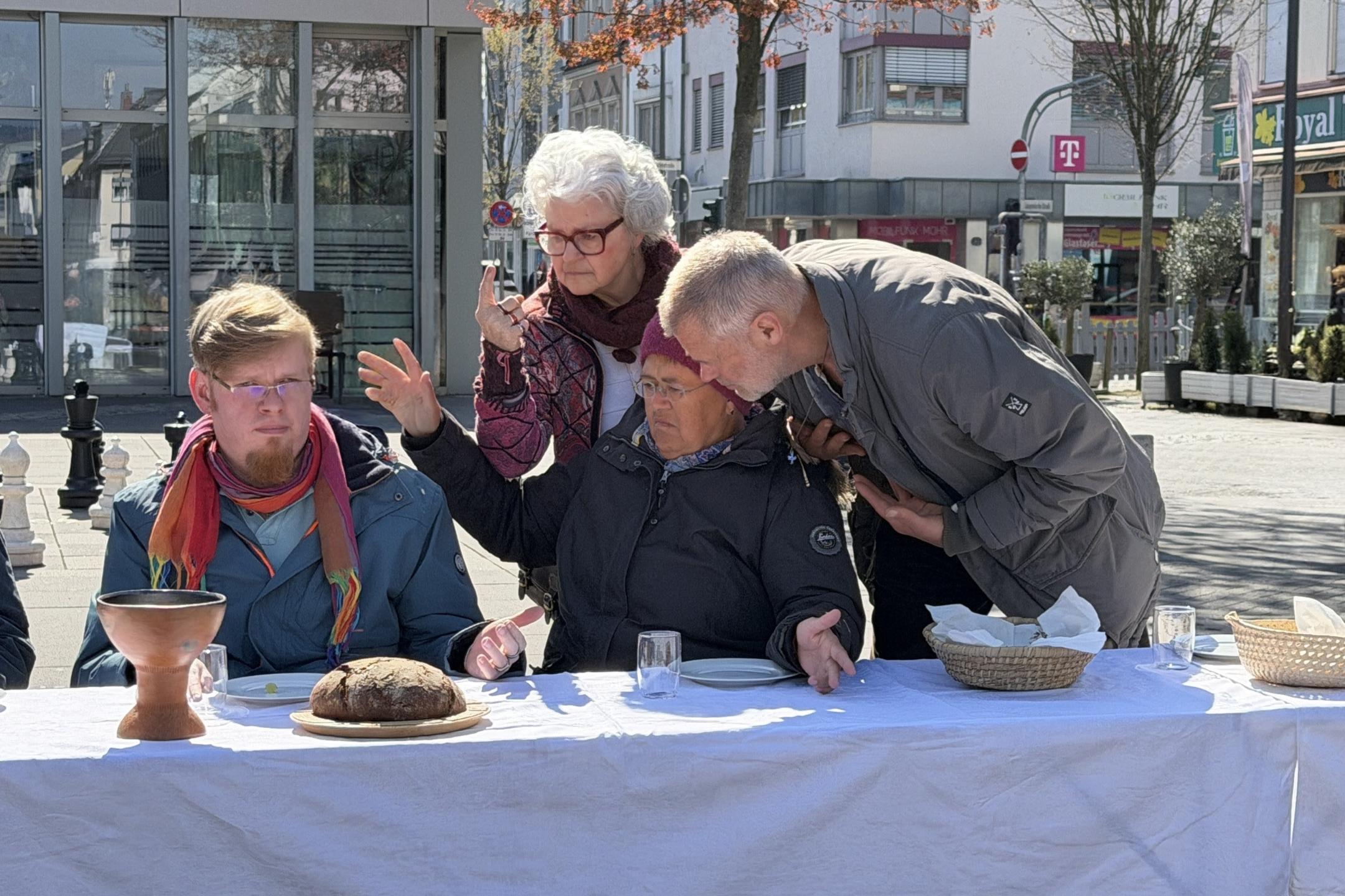 Der Jesus-Darsteller sitzt im Rollstuhl. Drei weitere Darsteller im fortgeschrittenen Alter beugen sich zu ihm.