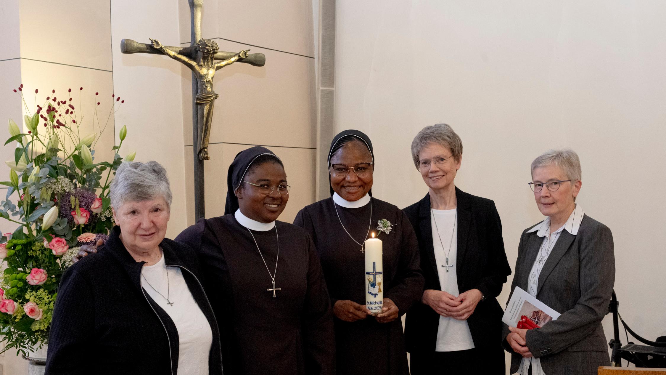 Die fünf Schwester, zwei in Tracht, die anderen in ziviler Kleidung, stehen in der Mutterhauskirche vor dem Kreuz.
