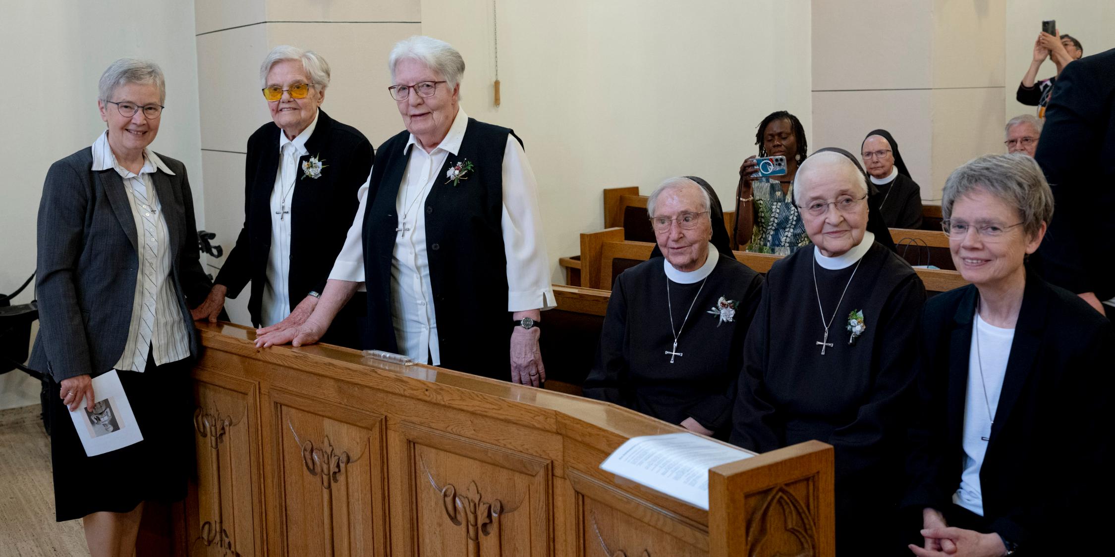Die ersten drei genannten Ordensschwestern (in ziviler Kleidung) stehen, die anderen drei (zwei in Ordenskleidung) sitzen in einer Kirchenbank.
