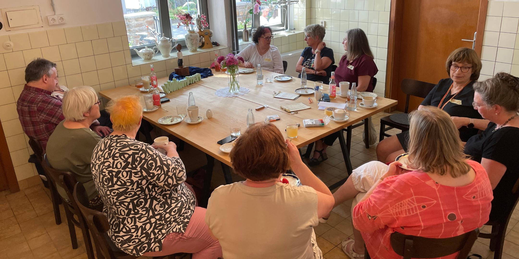 10 Frauen und ein Mann sitzen um einen gedeckten Tisch. (c) Petra Frey 10 Frauen und ein Mann sitzen um einen gedeckten Tisch.