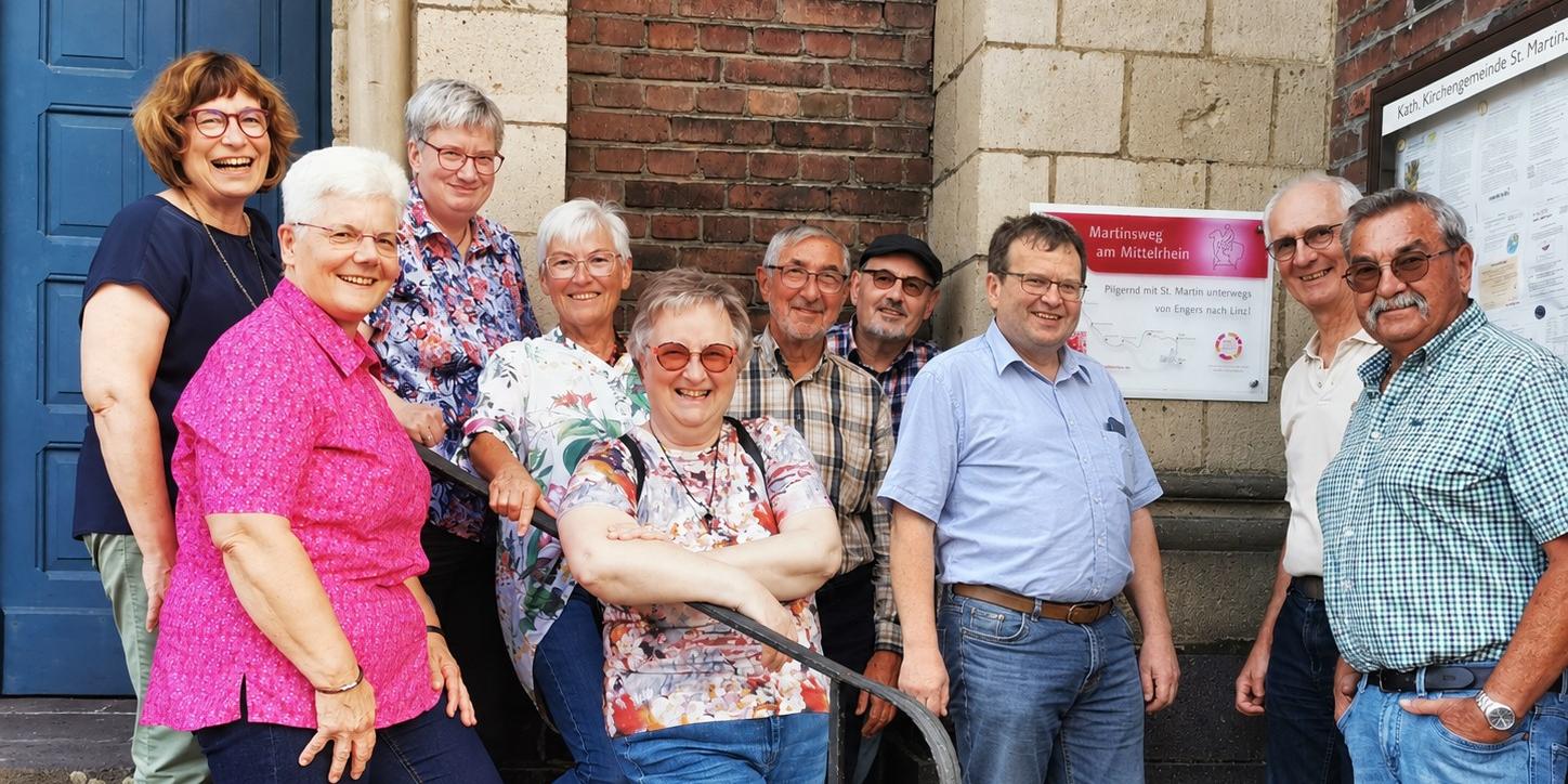 neues Hinweisschild Martinsweg in Engers: 30.09.2026 (c) Andreas Kossmann, Bild bearbeitet mit ChatGPT Mitglieder der Initiativgruppe Martinsweg am Mittelrhein und der Stiftung Sankt Martin Engers trafen sich am neu-angebrachten Hinweisschild an der Engerser Kirche St. Martin.