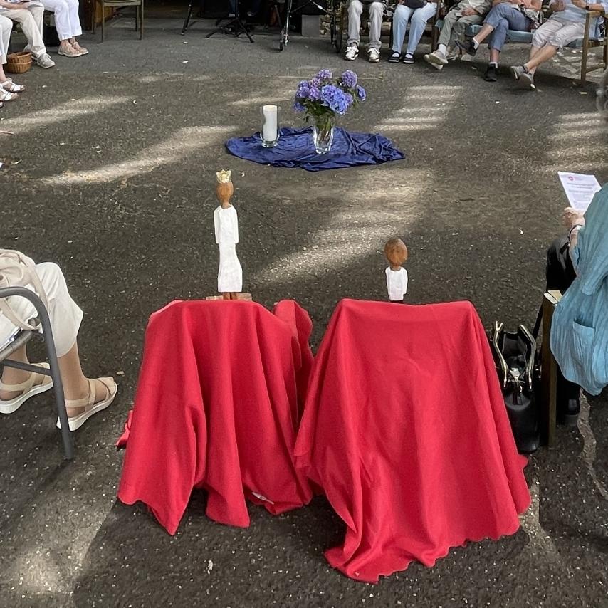 Die Königsfiguren stehen jede für sich auf einem mit einem roten Tuch verkleideten Hocker, im Kreis der Teilnehmerinnen.