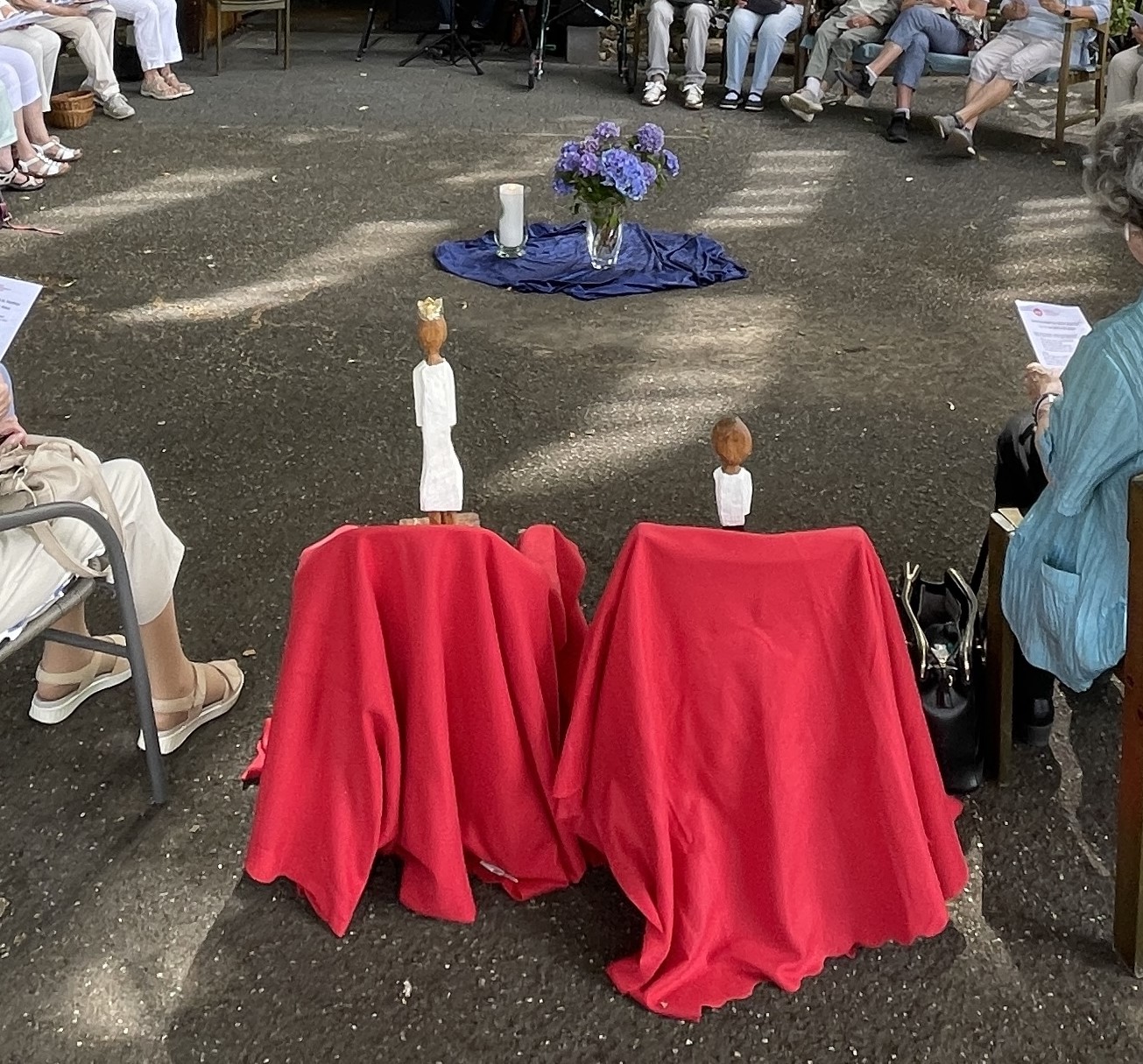 Die Königsfiguren stehen jede für sich auf einem mit einem roten Tuch verkleideten Hocker, im Kreis der Teilnehmerinnen.