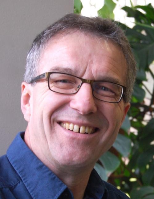 Der ergraute End-Sechziger mit kurzen Haaren, schmalem Gesicht und Brille lächelt in die Kamera.