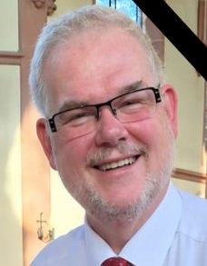 Pfarrer Christian Scheinost ist verstorben. Das Bild zeigt ein Portrait von Pfarrer Scheinost, das in der oberen rechten Ecke mit einem schwarzen Streifen versehen ist.