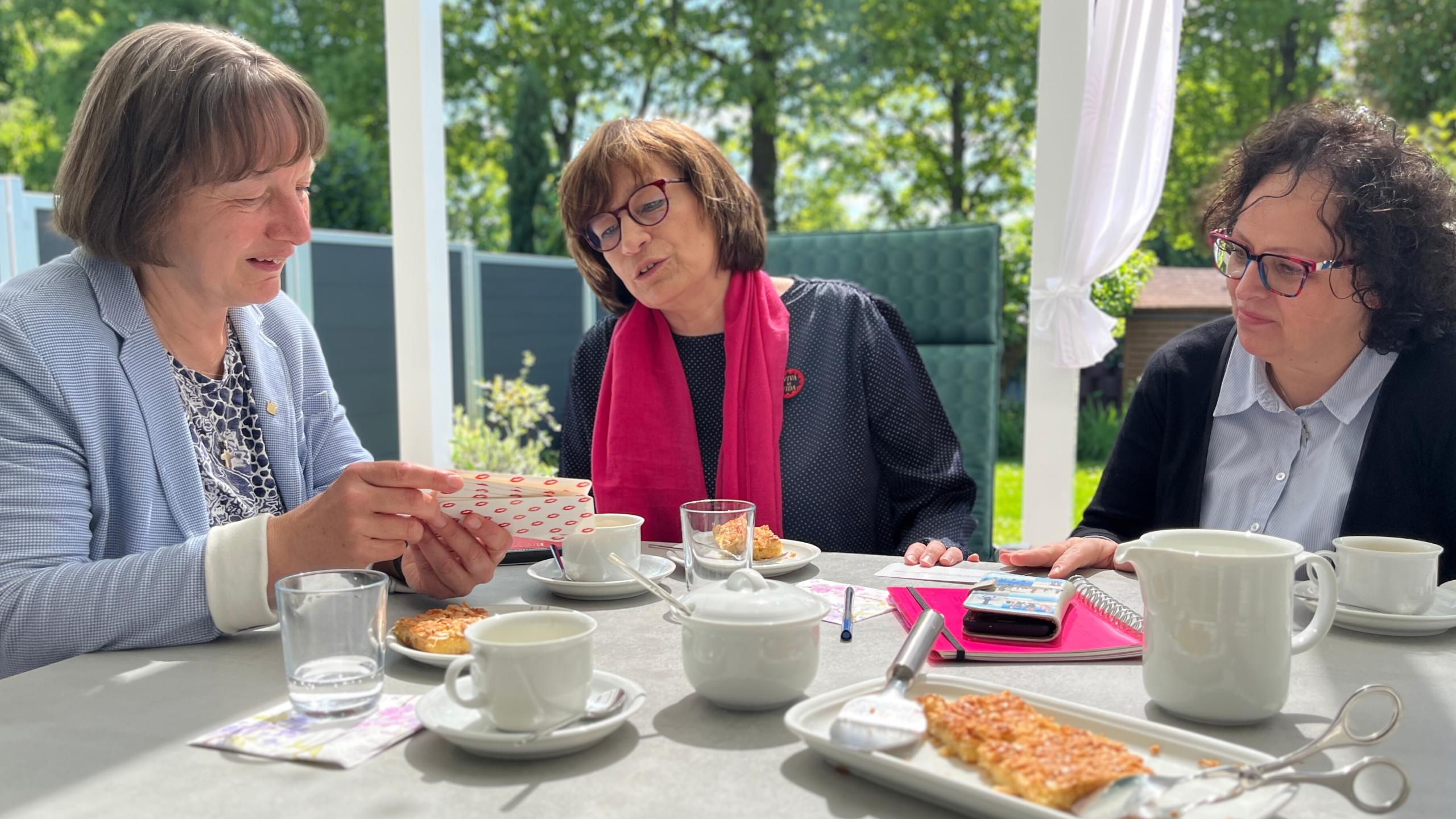 An einer gedeckten Kaffeetafel unterhalten sich die Verantwortlichen.