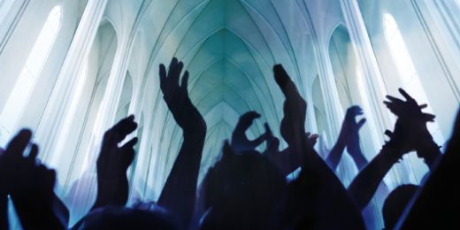 Menschen recken ihre Hände jubelnd und klatschend dem in Blau- und Grüntönen angestrahlten Kirchendeckengewölbe entgegen.
