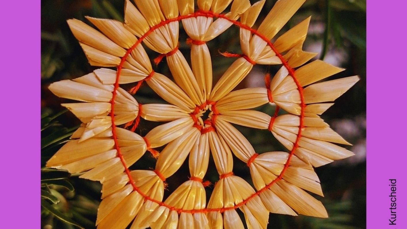 Das auf einem violetten Hintergrund gesetzte Bild zeigt einen Strohstern.