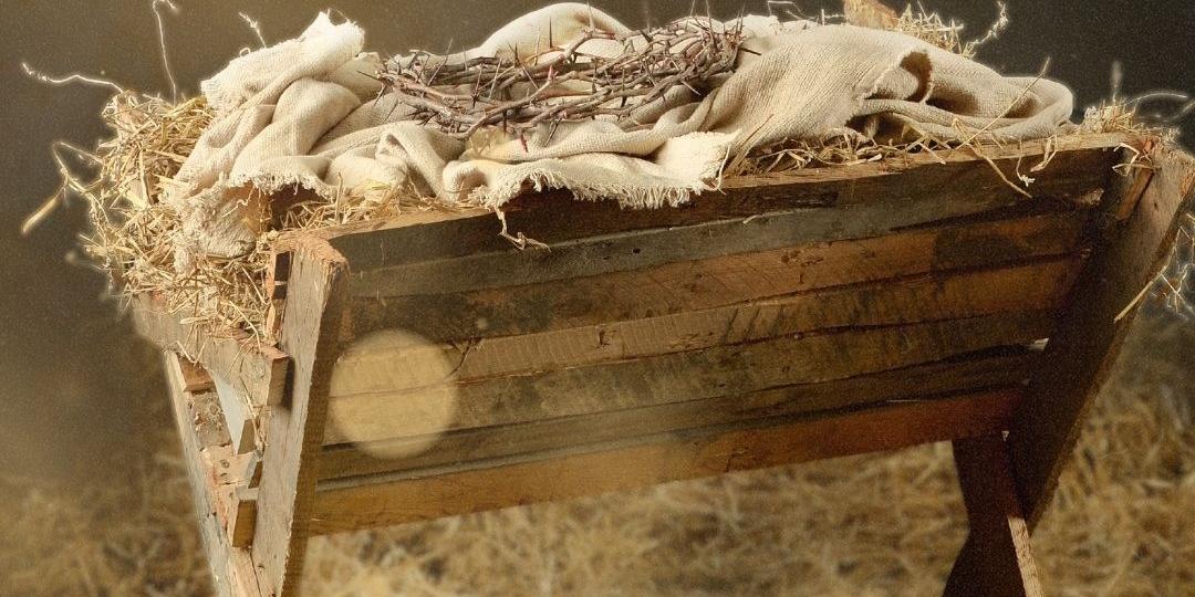 Das Hintergrundbild des Plakates zeigt eine eine Futterkrippe aus Dachlatten. Auf dem Heu liegt ein Windeltuch und darauf eine Dornenkrone.
