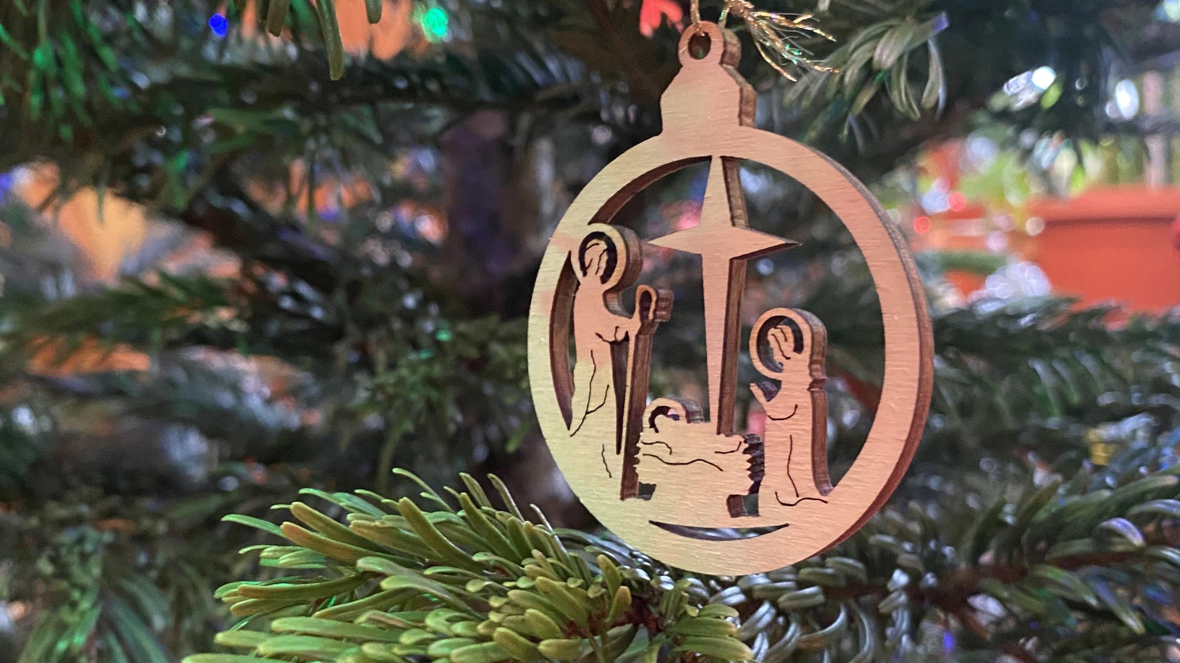 Der Holzanhänger im Weihnachtsbaum zeigt eine Darstellung der Heiligen Familie mit dem Weihnachtsstern.