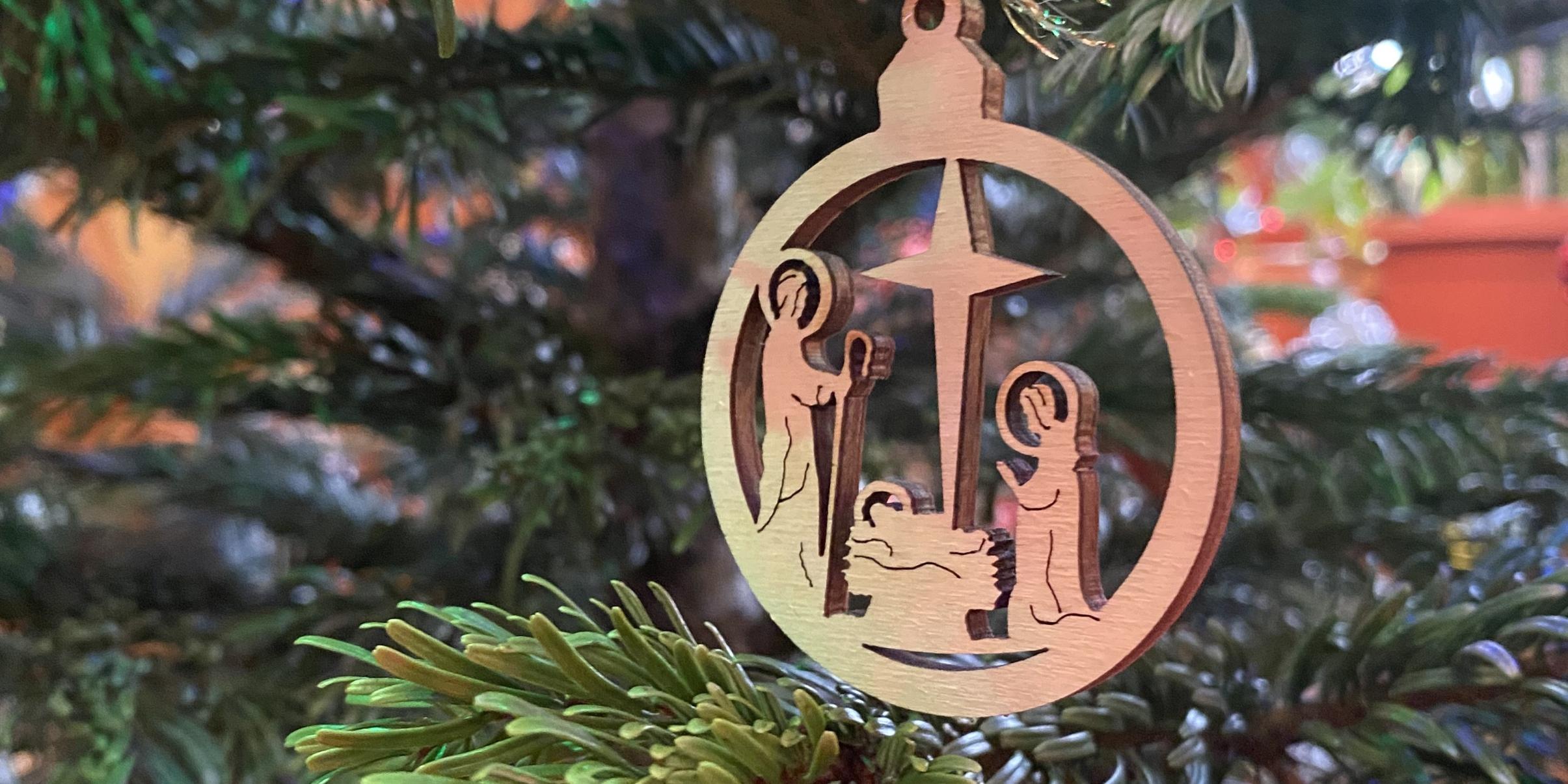 Der Holzanhänger im Weihnachtsbaum zeigt eine Darstellung der Heiligen Familie mit dem Weihnachtsstern.