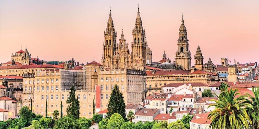 Am Abendlicht erscheint der Himmel über der Kathedrale in orange-rosa Farbtönen. Die Kathedrale liegt etwas versteckt hinter weiteren Gebäuden der Altstadt.