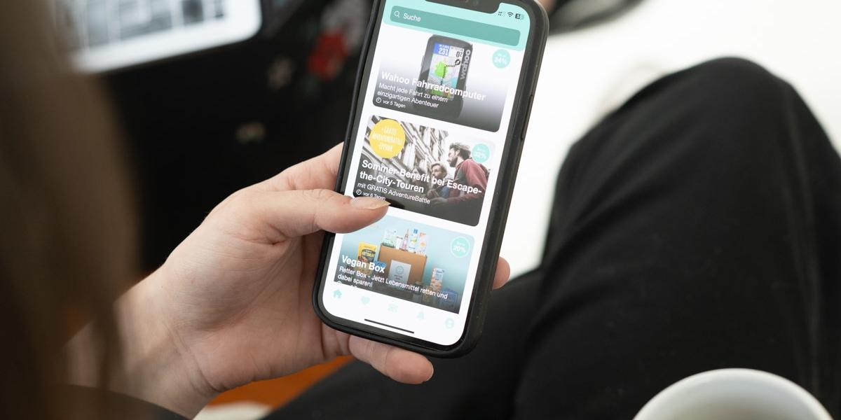benefits.me-App (c) benefits.me Eine linke Hand hält ein Smartphone, auf dem die App 'benefits.me' aufgerufen ist.