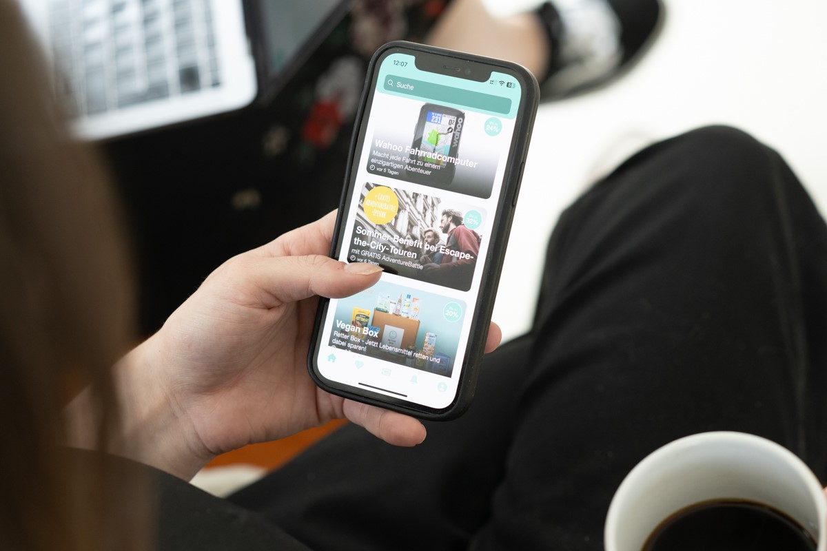 Eine linke Hand hält ein Smartphone, auf dem die App 'benefits.me' aufgerufen ist.